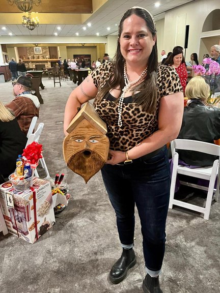 A guest holding a hand-carved wooden gift basket item